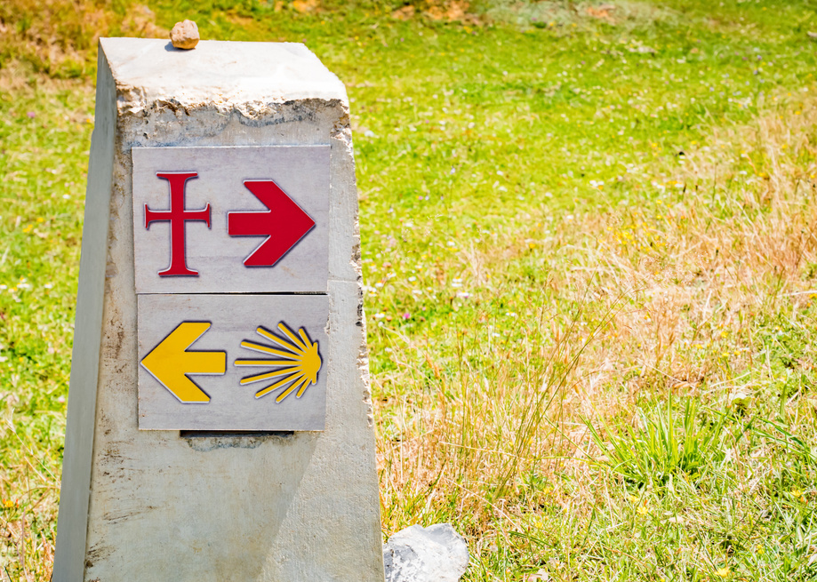 Traditional shell sign and arrow painted on the way. Direction sign for pilgrims in Saint James way, Camino de Santiago de Compostela, Camino Vadiniense y Lebaniego, Spain