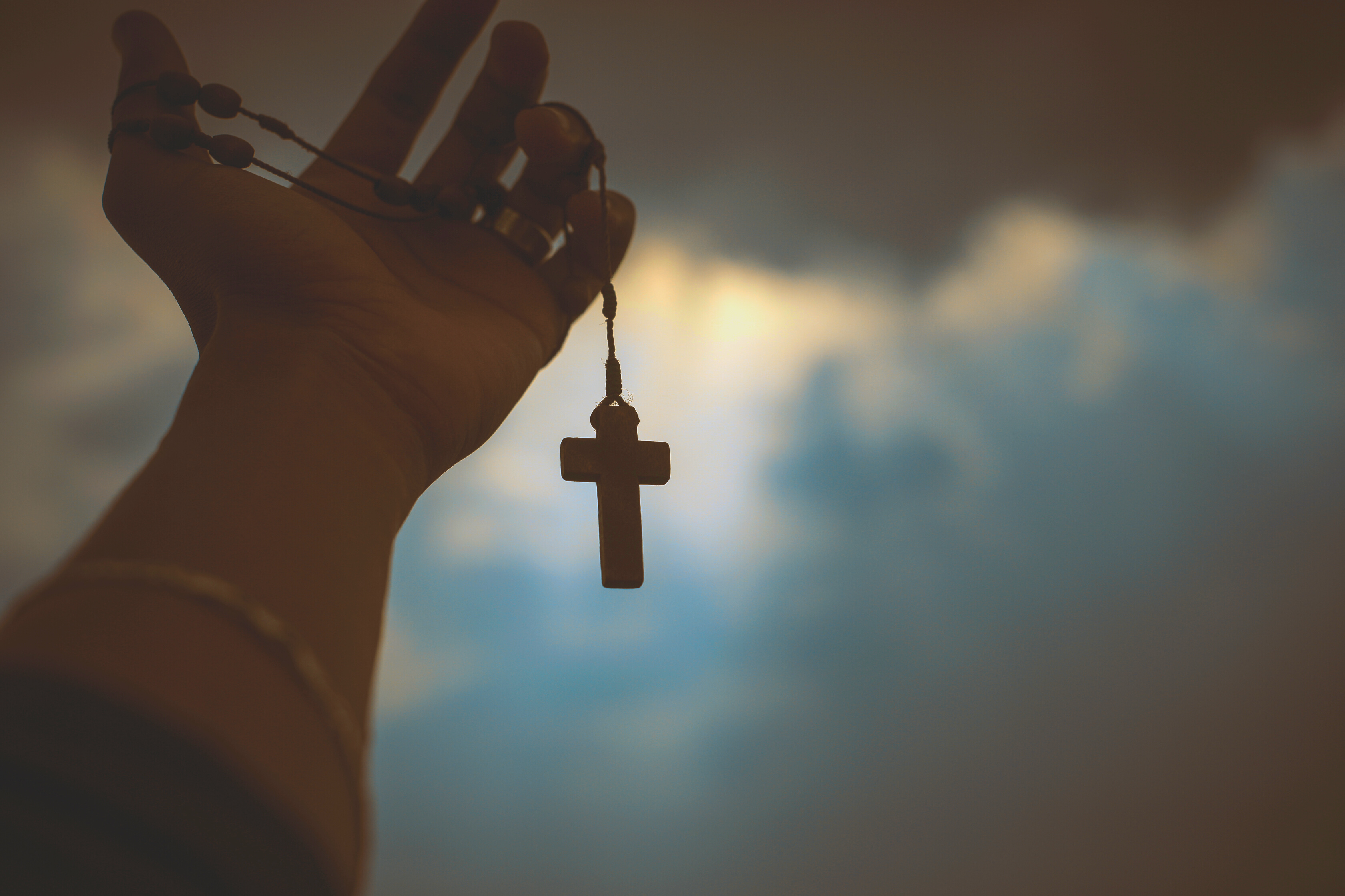 Person Holding Brown Wooden Cross